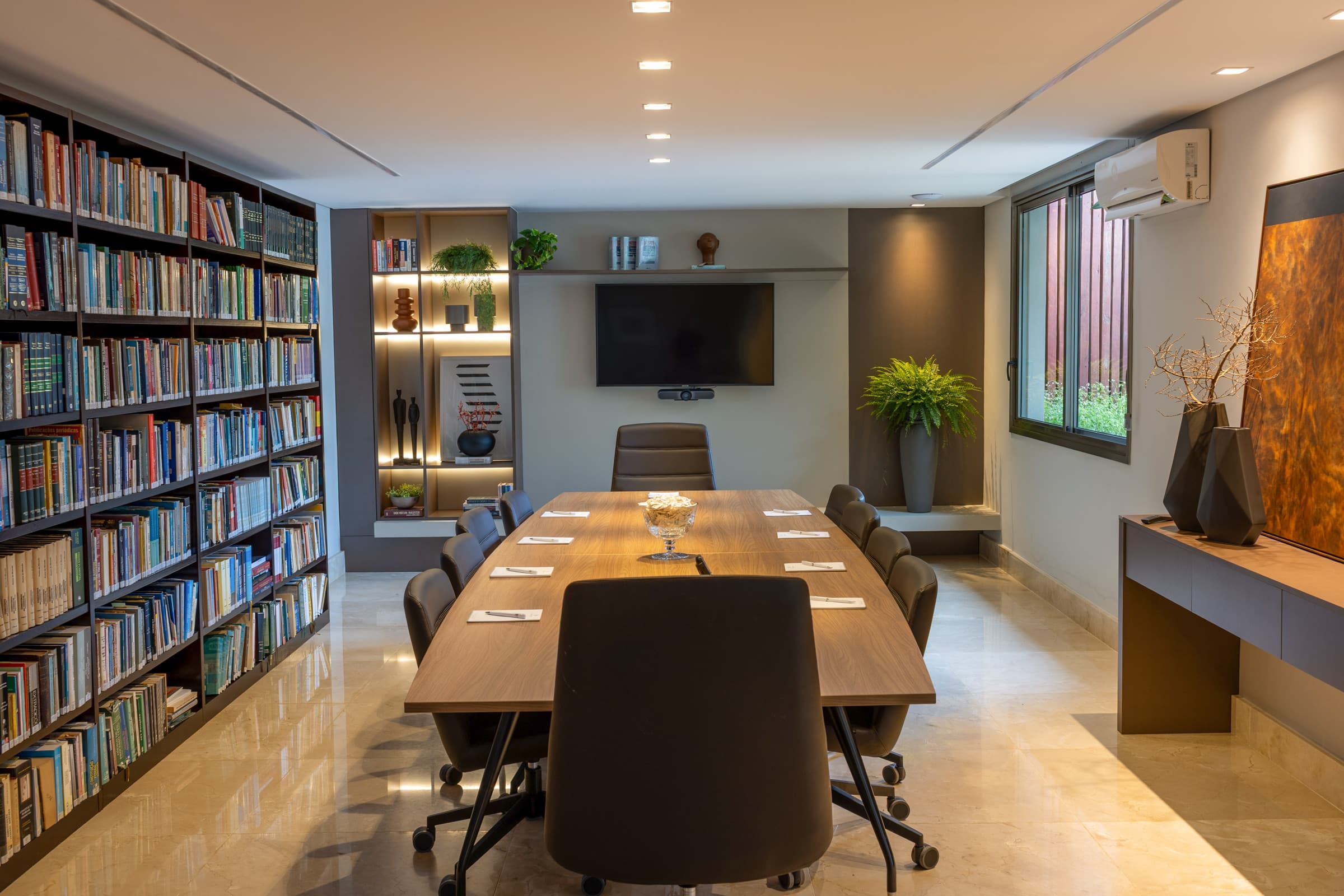 Sala de reuniões com biblioteca jurídica ao fundo